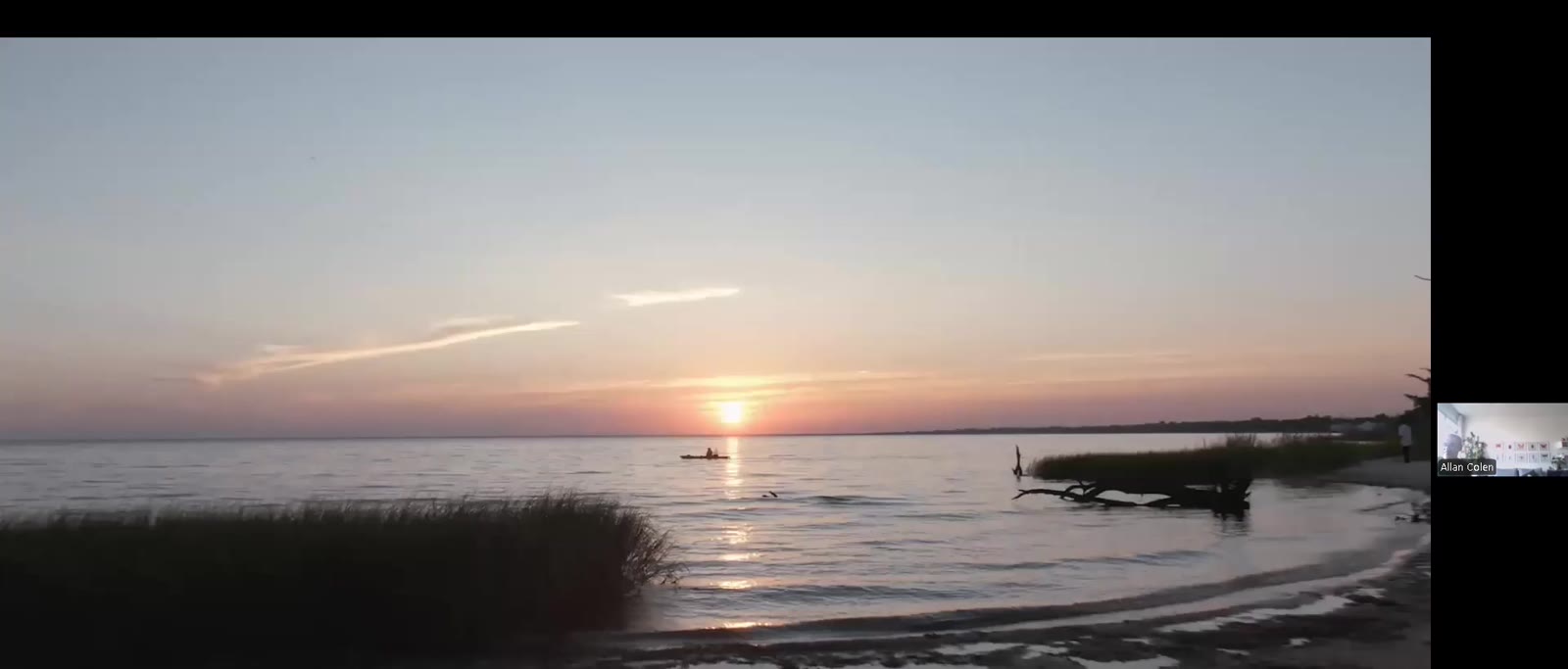 Por do sol sobre agua calma e barcos na costa