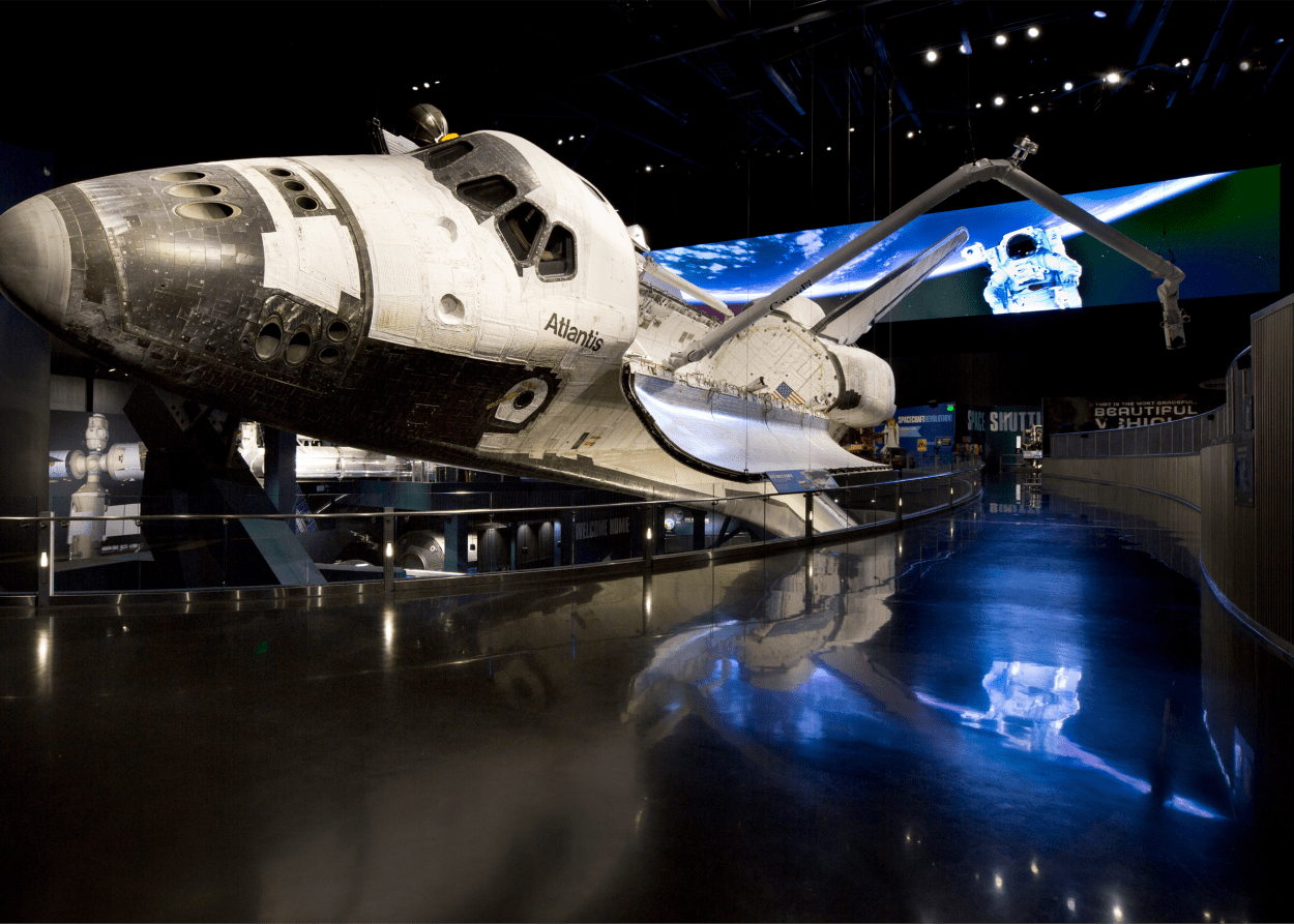 Ônibus espacial Atlantis em exposição com imagem orbital ao fundo